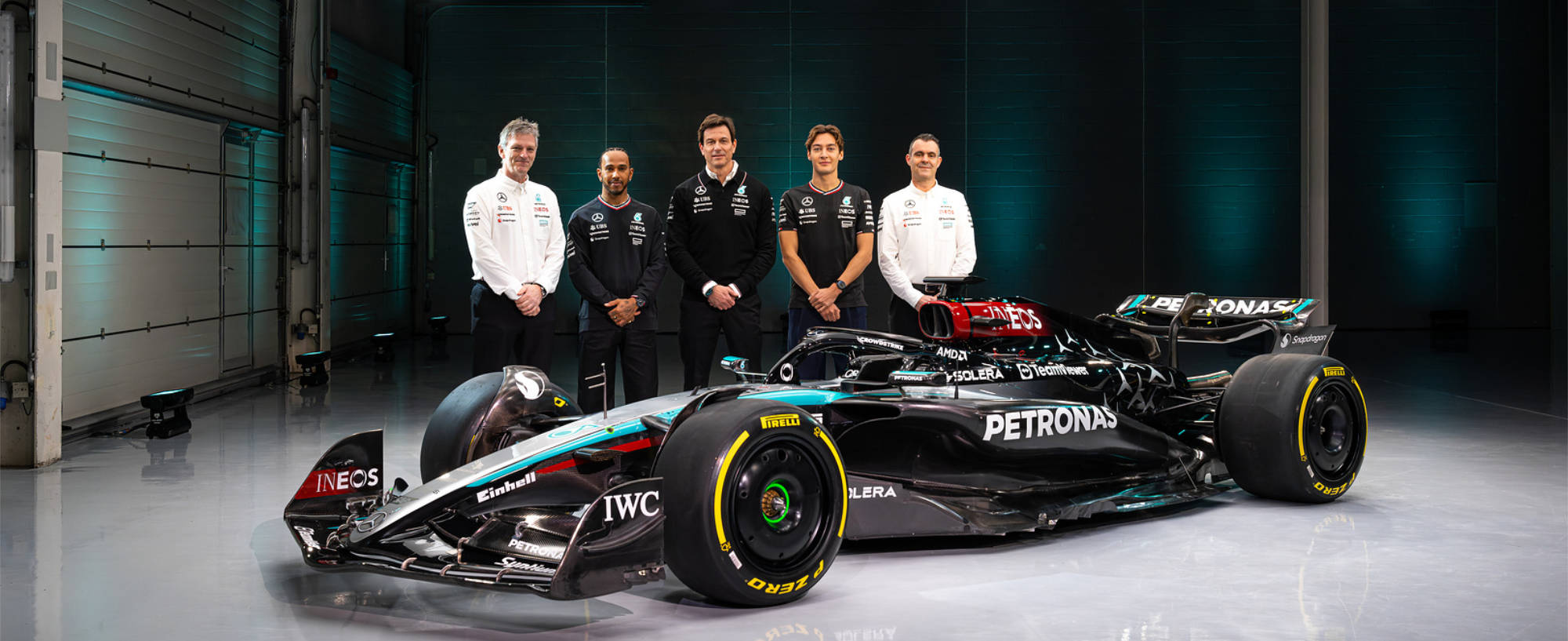Mercedes stand behind their W15 in a garage at Silverstone, where they announced their new car for 2024