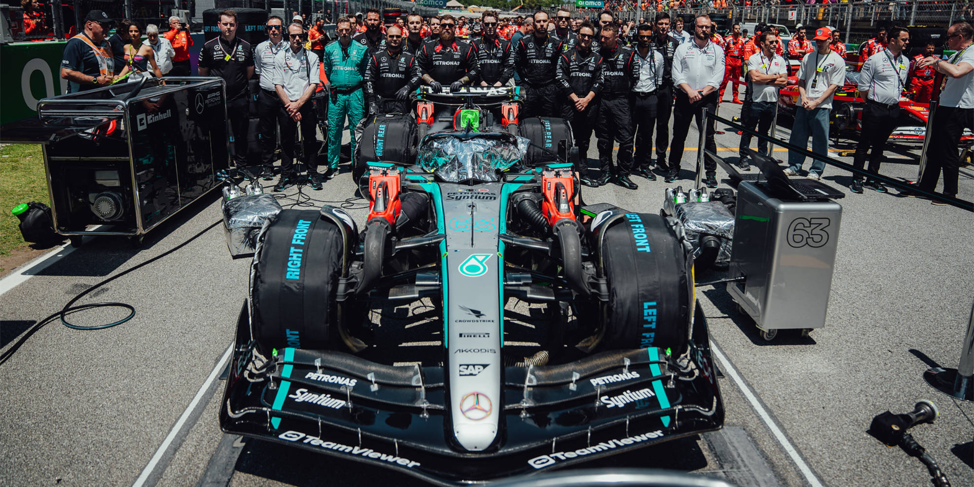 Mercedes team stand behind George Russell's 63 car on the starting grid at the Spanish Grand Prix. 