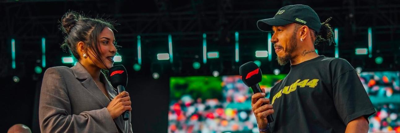 Ariana Bravo and Lewis Hamilton interviewing, looking at each other on the Silverstone main stage