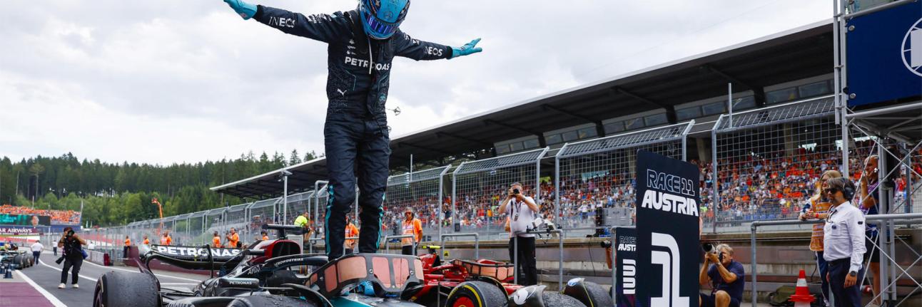 Russell Stands on his car celebrating his win in a t pose