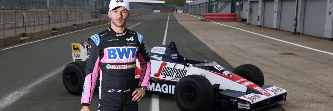 pierre gasly stands in front of ayrton senna's toleman f1 car