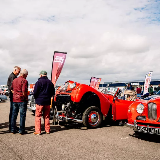 classic car with bonnet open - attendees talking around vehicle