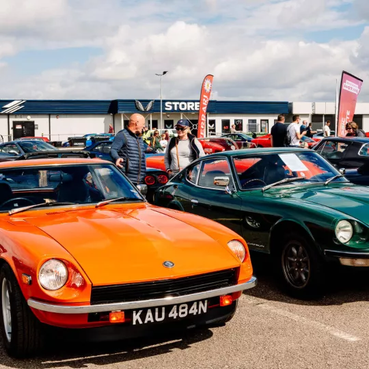 two cars, orange and green, orange in foreground