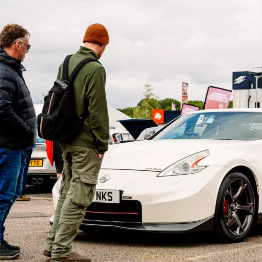 two people look at white sports car 