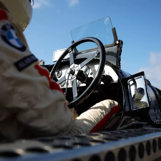 Driver in car, low, close shot of wheel and the driver