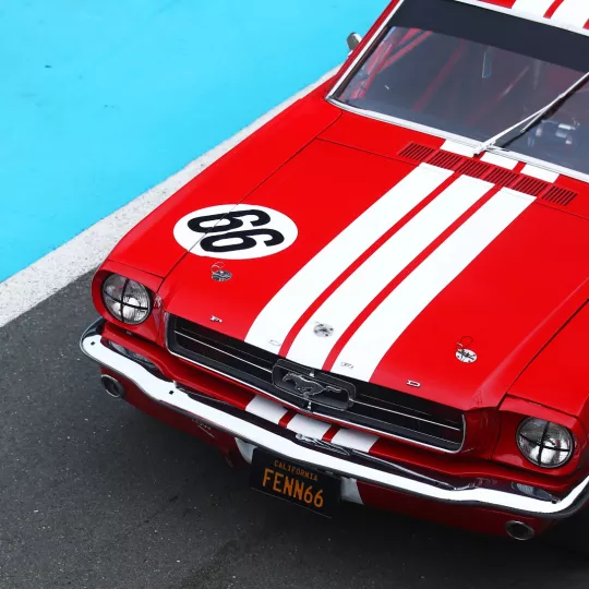 a red car with white stripe goes around a corner on track