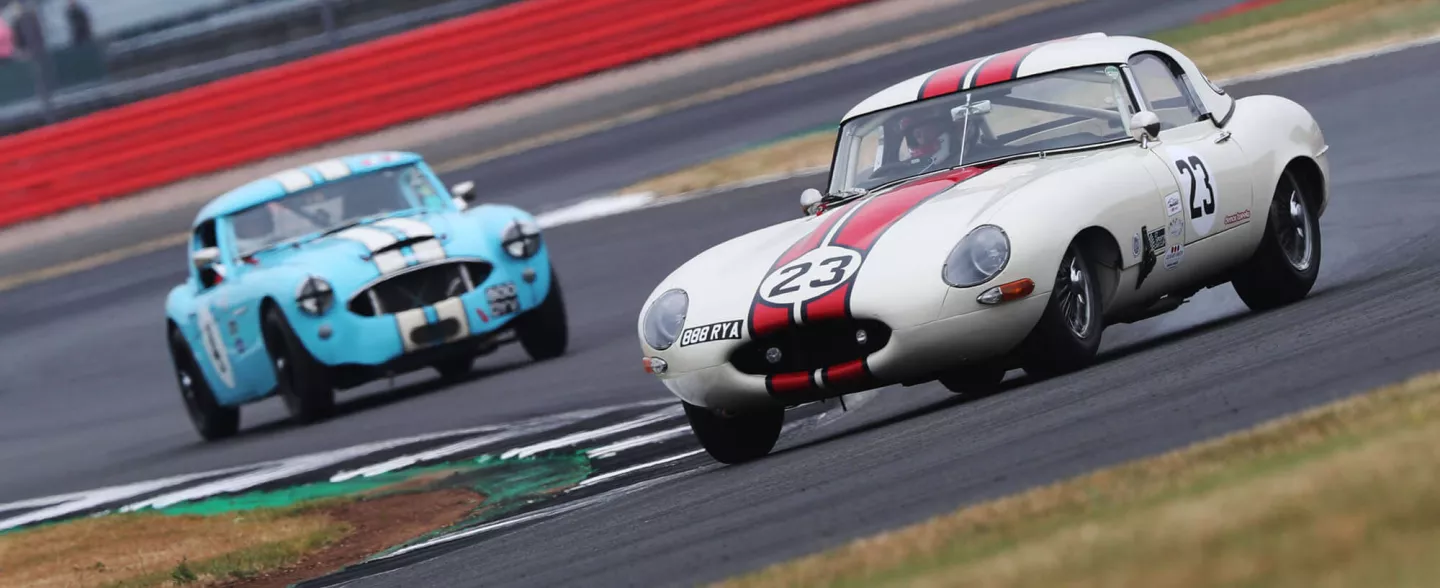 Two classic race cars from the early '60s competing in the Royal Automobile Club Tourist Trophy For Historic Cars at The Classic at Silverstone